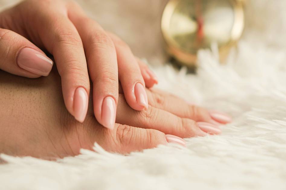Elegant close-up of glossy nude nail polish top coat on manicured hands with soft neutral background
